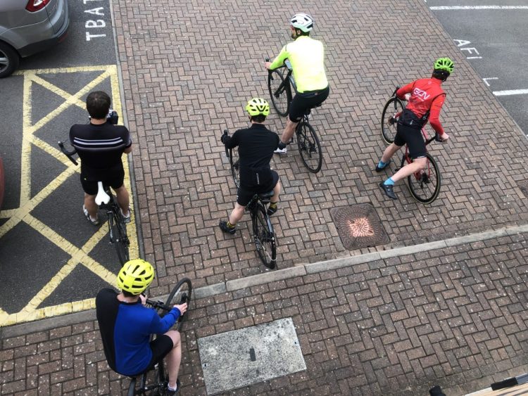 5 cyclists mounting their bikes in an office car park