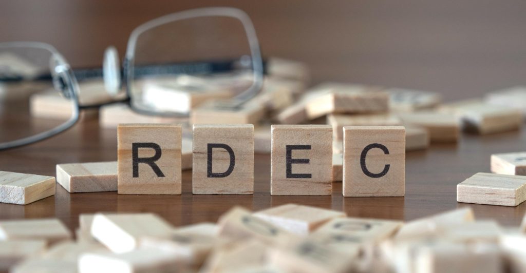 the acronym rdec for research and development expenditure credit word or concept represented by wooden letter tiles on a wooden table with glasses and a book
